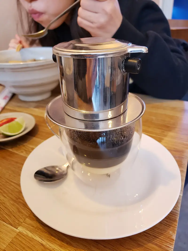 A steel phin over a glass of black coffee